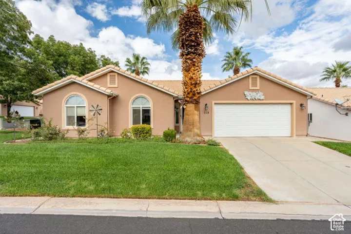 Single-story stucco exterior featuring arched windows, a tile roof, an attached two-car garage, and mature palm landscaping