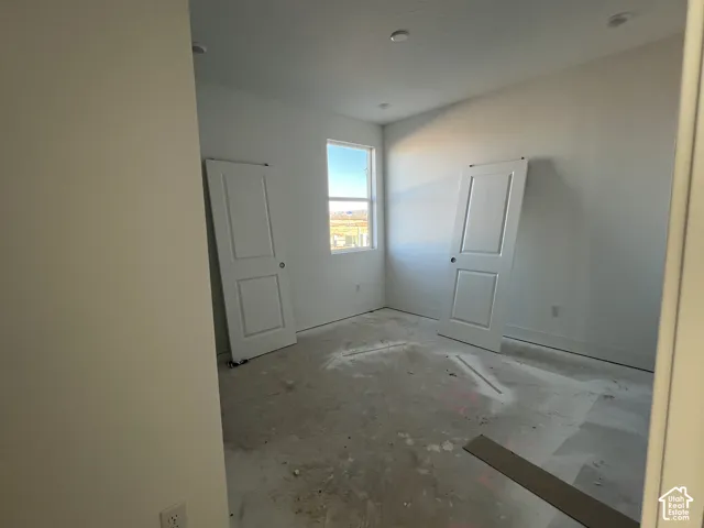 Room interior featuring recessed ceiling lighting, a single pane window, and two multi-panel interior doors
