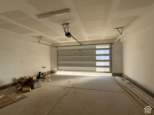 Attached garage featuring drywall finishes, a metal sectional door with integrated glass panels, and a ceiling-mounted automatic door opener