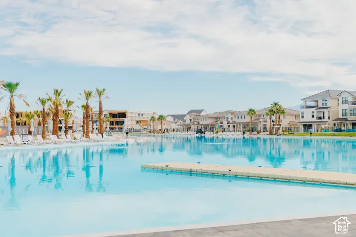 Large-scale turquoise swimming lagoon featuring a central floating dock, paved perimeter, and surrounding palm trees