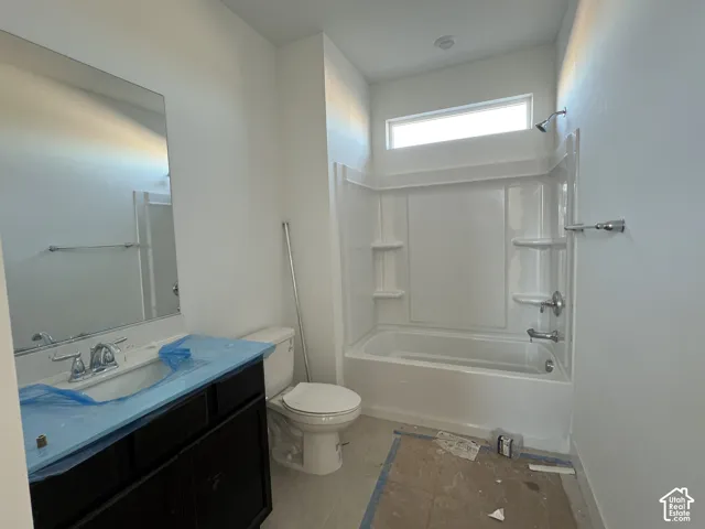 Bathroom featuring a dark wood-finish vanity, large wall-mounted mirror, white tub-shower combination with integrated shelving, and a horizontal transom window