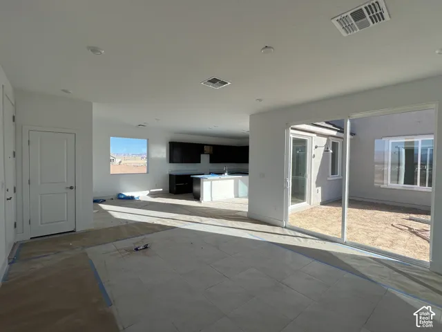 Open-concept interior featuring large-format tile flooring, sliding glass doors, dark-finish kitchen cabinetry, and an integrated kitchen island