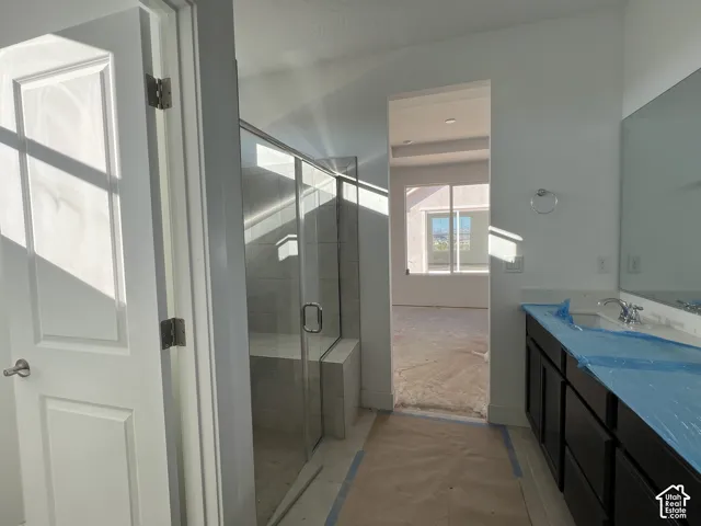 Glass-enclosed shower with tiled surround and integrated bench, dark wood-finish cabinetry, countertop with undermount sink, and full-width wall mirror