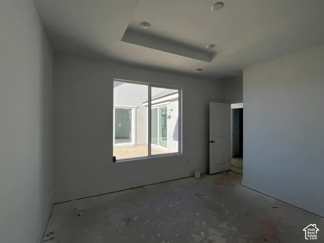 Interior space featuring a recessed tray ceiling with integrated lighting, large rectangular window, and paneled interior door
