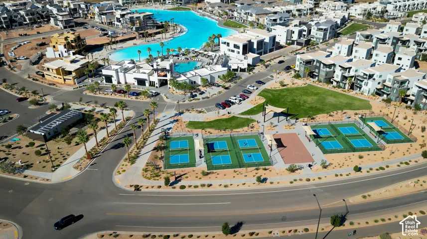Aerial perspective featuring multi-sport courts, manicured green space, paved walkways, and a large recreational pool facility
