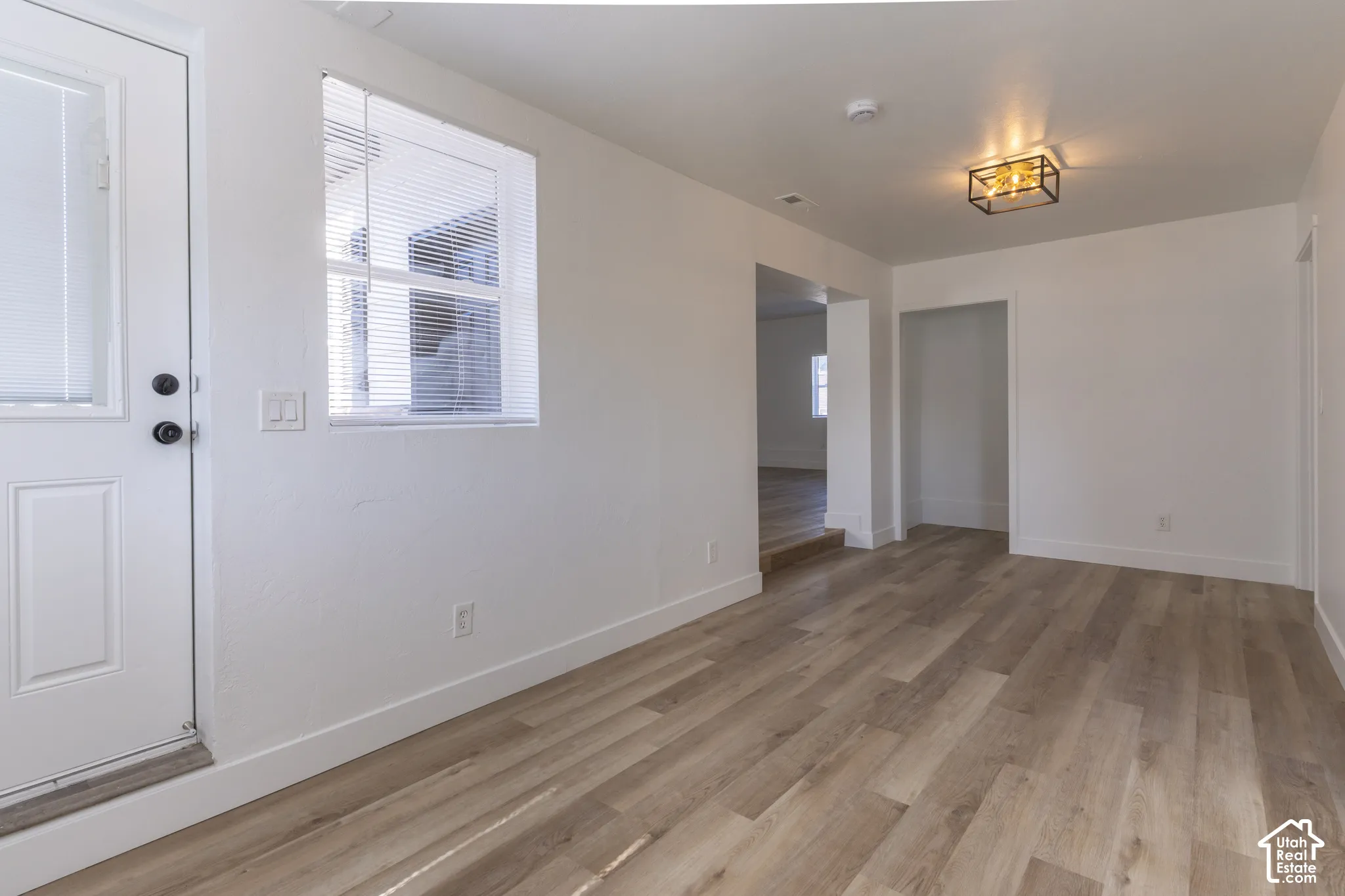 Oversized entry with new LVP and lighting. View looking into main floor family room