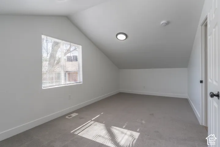 Primary bedroom with vaulted ceilings, a built-in skylight, and new carpet.