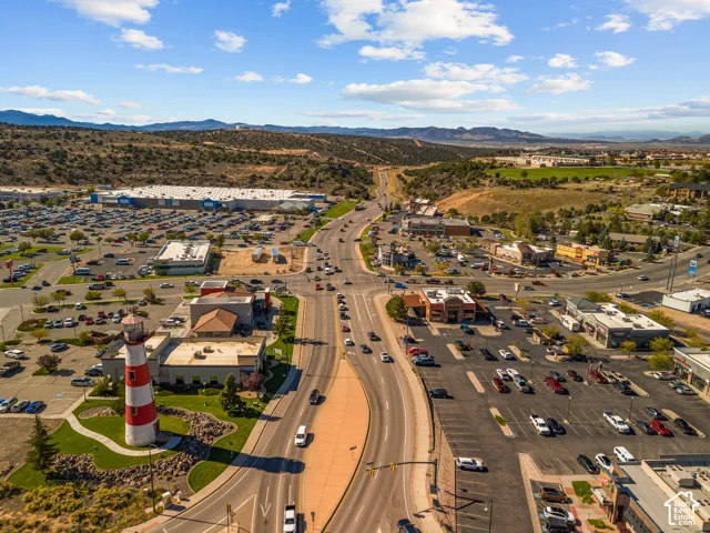 Aerial perspective featuring a prominent lighthouse structure, extensive paved parking infrastructure, established roadway access, and a mountainous horizon