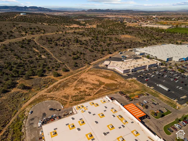 Aerial perspective featuring expansive undeveloped terrain, mountain range horizon, and surrounding commercial infrastructure