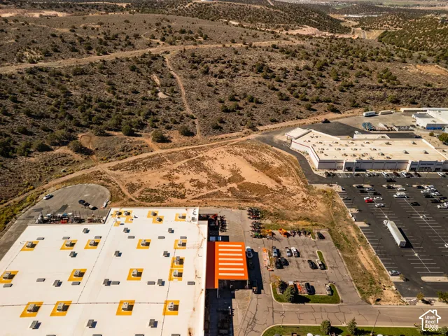 Expansive commercial parcel featuring paved parking areas, a large-scale industrial structure with a prominent entrance canopy, and direct access to adjacent thoroughfares