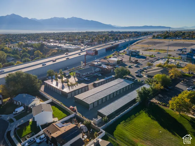 Aerial perspective featuring a multi-unit storage complex, paved drive aisles, perimeter fencing, and mountain range backdrop
