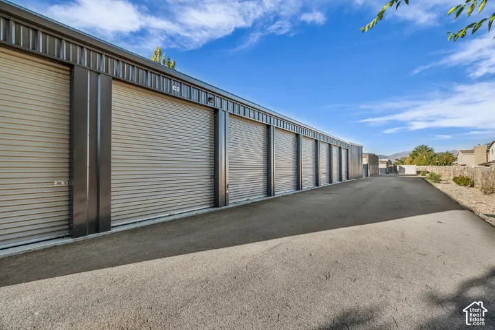 Metal-siding storage facility featuring multiple rolling steel garage doors, dark metal trim, and paved exterior access