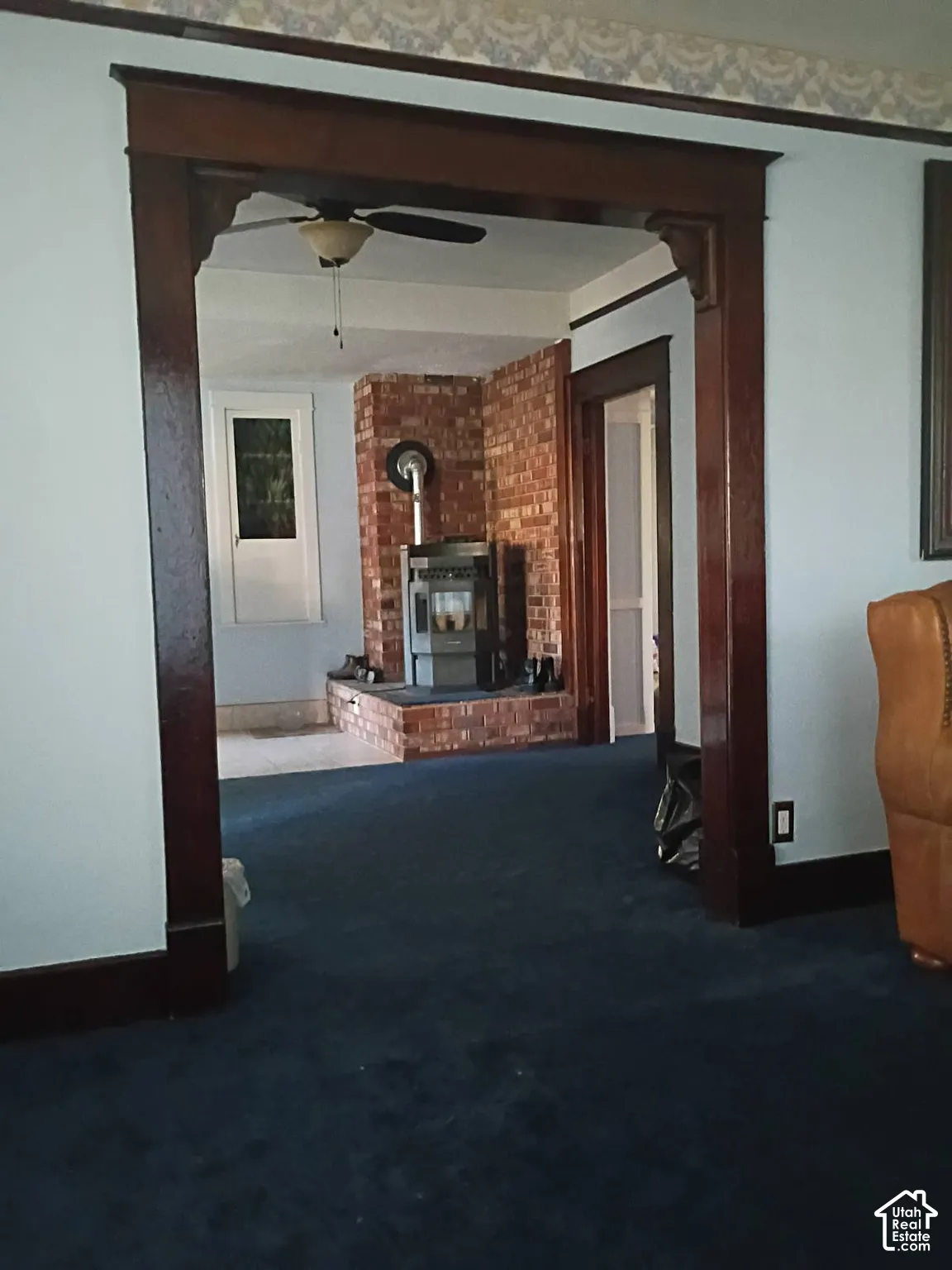 Stained wood cased opening with decorative corbels, brick chimney feature, and integrated wood-burning stove on a raised brick hearth