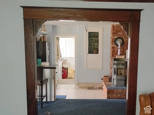 Stained wood doorway featuring decorative corner brackets, exposed brick surround, and tiled flooring