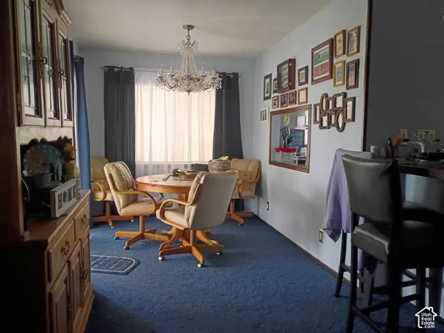 Dining space featuring a tiered crystal chandelier, wall-mounted mirror, and carpeted flooring