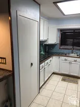 Kitchen featuring white cabinetry, dark tiled countertops, a recessed ceiling light, and ceramic floor tiling