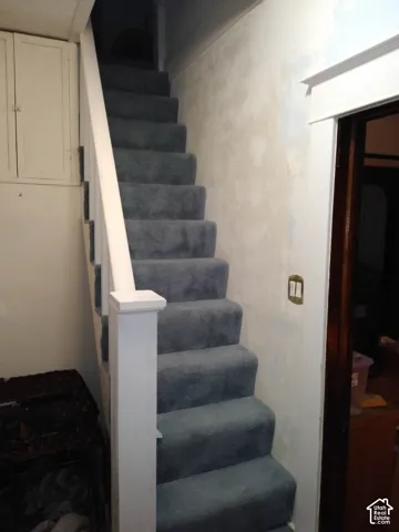 Staircase featuring wall-to-wall carpeting, white painted wood banister, and built-in cabinetry