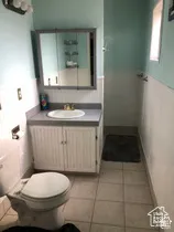 Bathroom featuring white beadboard cabinetry, integrated vanity top with a circular basin, tri-fold medicine cabinet, and tiled flooring