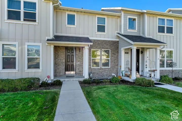 Multi-unit exterior featuring vertical siding, stone veneer accents, covered entryway, and asphalt shingle roofing