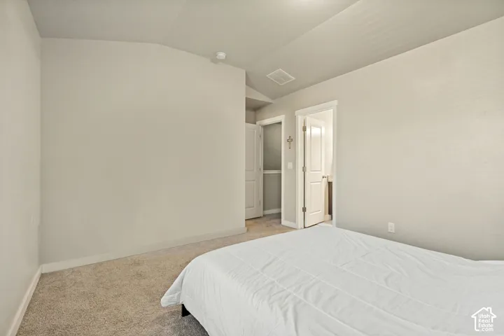 Interior space featuring vaulted ceilings, neutral wall tones, and neutral-toned carpeting throughout