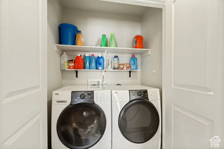 Laundry area featuring white high-efficiency front-load appliances and two levels of white built-in shelving