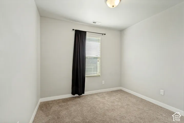 Neutral-toned walls, plush wall-to-wall carpeting, single-pane window with horizontal blinds, and a flush-mount ceiling fixture