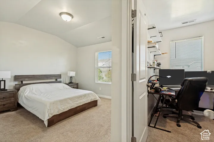 Vaulted ceilings, neutral carpeting, and large-paned windows featuring horizontal blinds