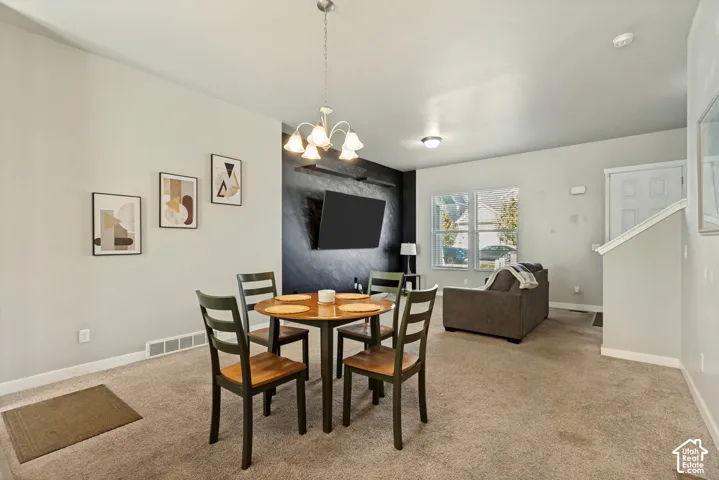 Open-concept room featuring a textured black accent wall, neutral carpeting, and a multi-arm pendant light fixture