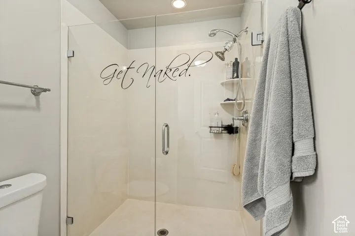 Walk-in shower featuring a frameless glass enclosure, polished chrome hardware, an adjustable handheld showerhead, and integrated shelving