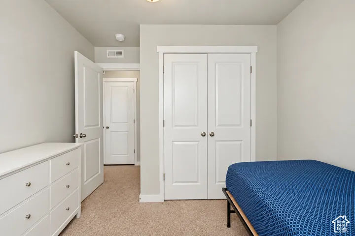 Neutral-toned interior featuring carpeting, dual-panel closet doors, and solid-core interior doors with satin nickel hardware