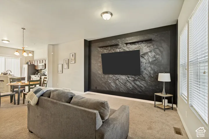 Living area featuring a textured dark accent wall, two floating display shelves, neutral carpeting, and horizontal window blinds