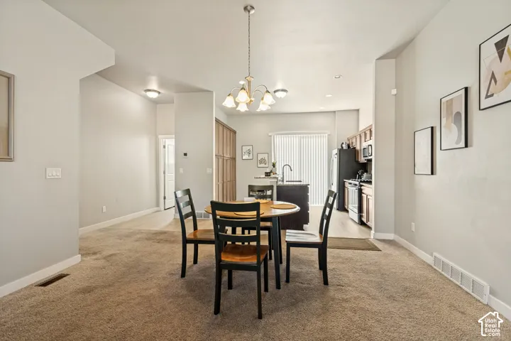 Open-concept area featuring a kitchen island with sink, multi-light hanging chandelier, wood-finish cabinetry, and sliding glass patio doors