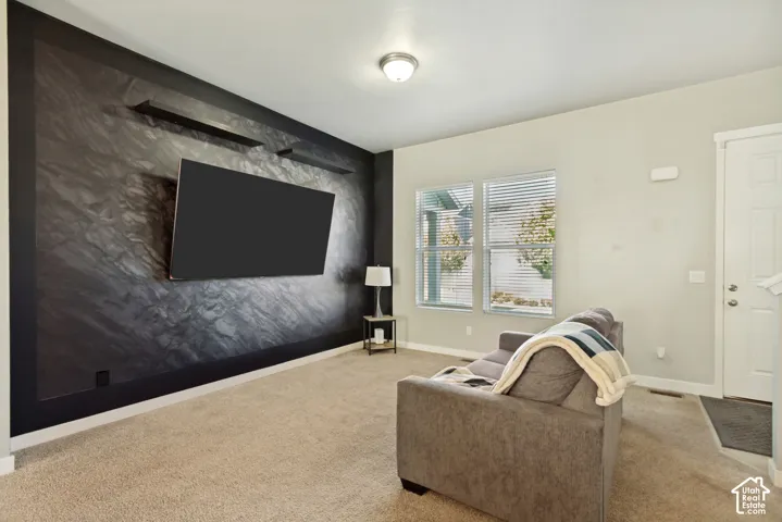 Textured dark accent wall with dual built-in floating shelves, neutral wall finishes, plush carpeting, and multi-pane windows with horizontal blinds