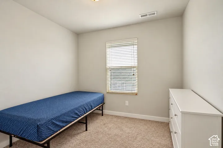 Neutral-toned walls, neutral carpeting, and a single-pane window featuring installed horizontal blinds