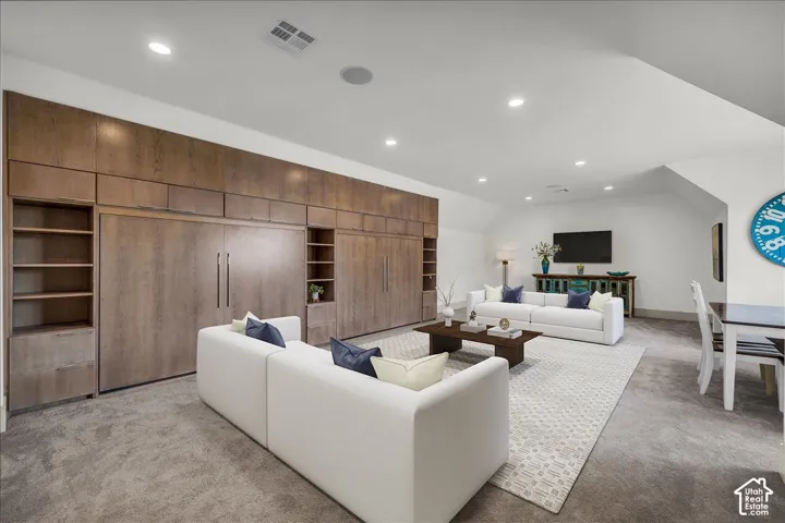 Extensive wall-to-wall built-in wood cabinetry featuring integrated storage, recessed ceiling lighting, and neutral carpeting