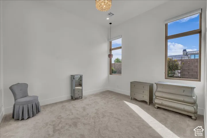 High ceilings, neutral carpeting, expansive windows with wood-finish frames, recessed lighting, and a crystal-style semi-flush mount ceiling fixture