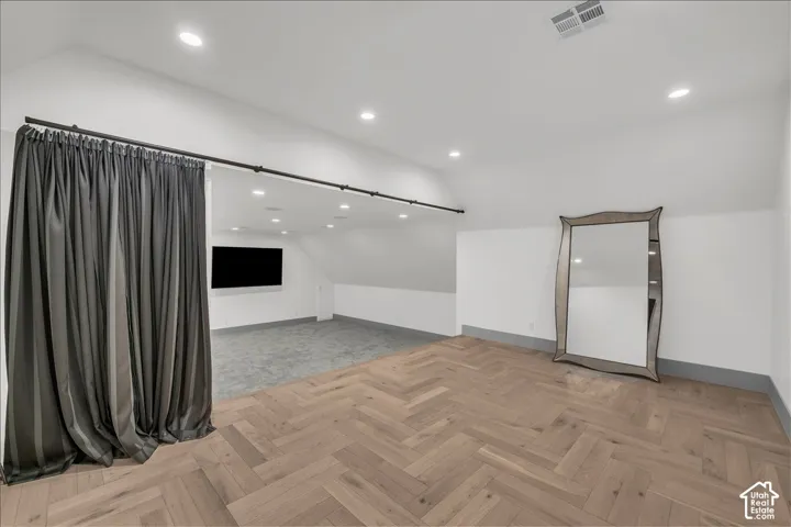 Herringbone-patterned wood-finish flooring, recessed lighting, and a wall-mounted television