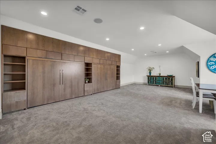 Expansive room featuring wall-to-wall carpeting, recessed ceiling lighting, and extensive floor-to-ceiling built-in cabinetry with integrated shelving