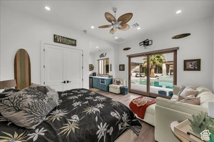 Recessed lighting, ceiling fan with palm-style blades, wood-finish flooring, built-in wet bar with cabinetry, and sliding glass doors
