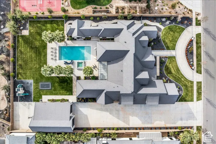 Aerial view featuring a multi-gabled residence with a concrete circular driveway, integrated swimming pool with an attached spa, and manicured lawn space