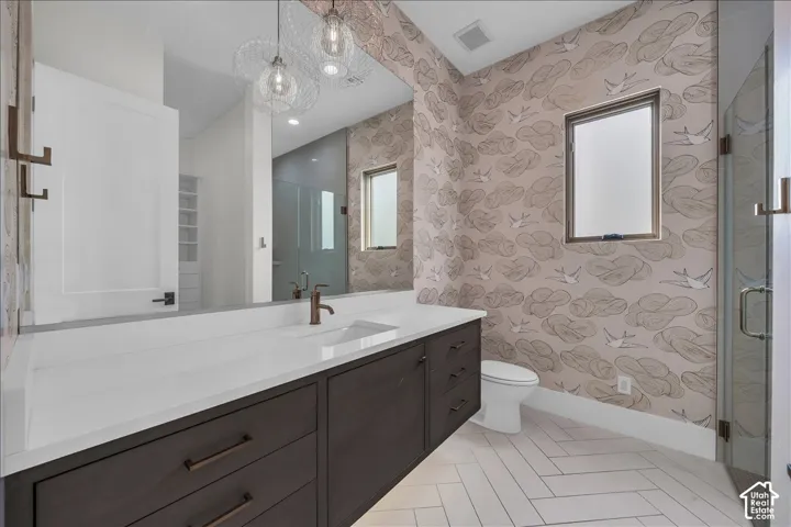 Dark-finish floating vanity with a stone countertop, under-mount sink, matte-finish hardware, and herringbone-pattern tile flooring