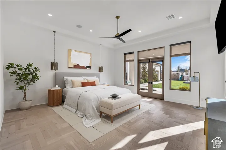 Herringbone-patterned wood-finish flooring, recessed tray ceiling, ceiling fan, and dual-pane glass doors with side windows providing outdoor access