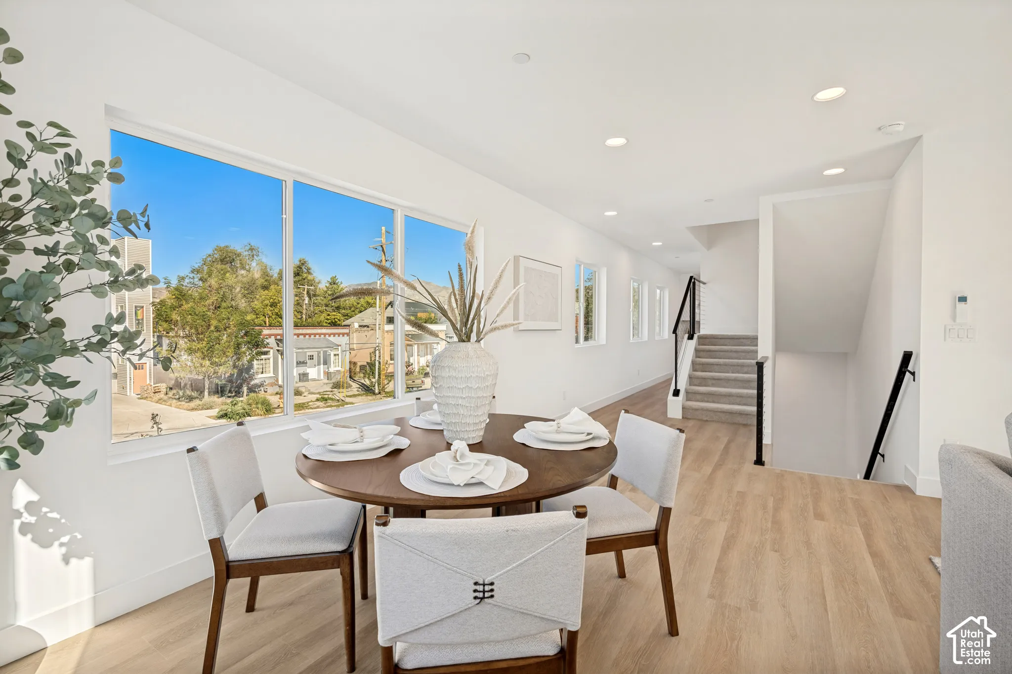 Large picture window, wood-finish flooring, recessed lighting, and staircase with a black metal handrail