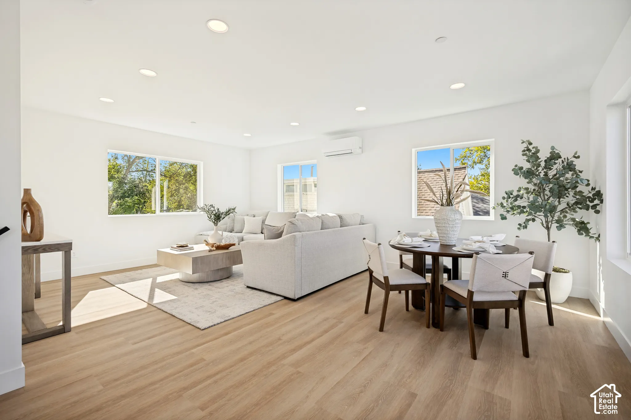 Open-concept interior featuring recessed lighting, wood-finish flooring, dual-pane sliding windows, and a wall-mounted ductless climate control unit