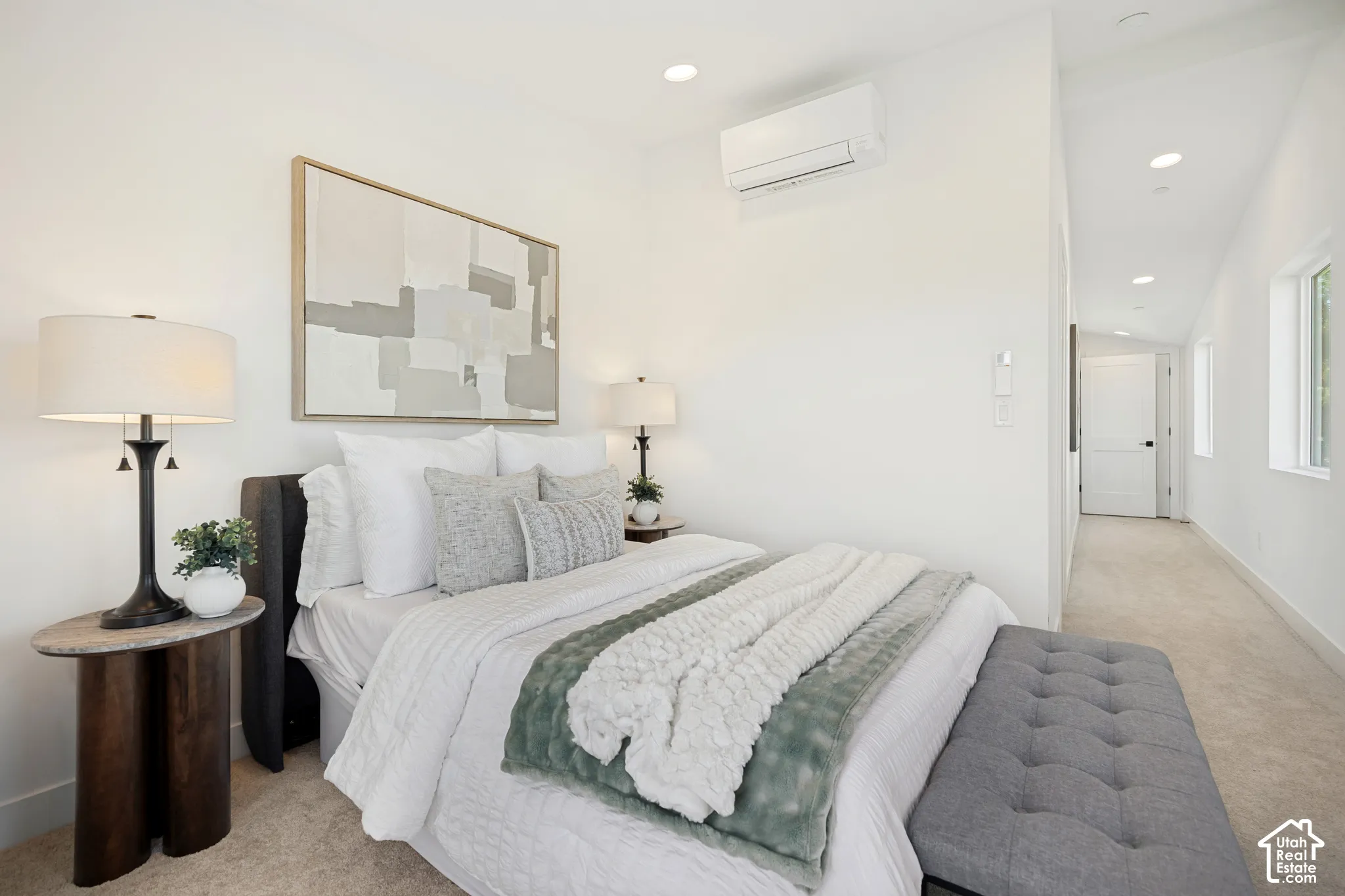 Neutral-toned interior featuring wall-to-wall carpeting, vaulted ceilings, recessed lighting, and a wall-mounted ductless climate control unit