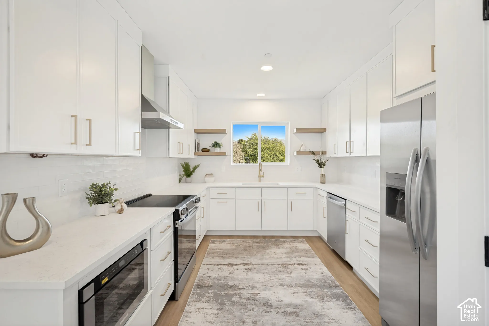 Kitchen featuring white shaker-style cabinetry, quartz countertops, stainless steel appliances, open wood-finish shelving, and wood-finish flooring