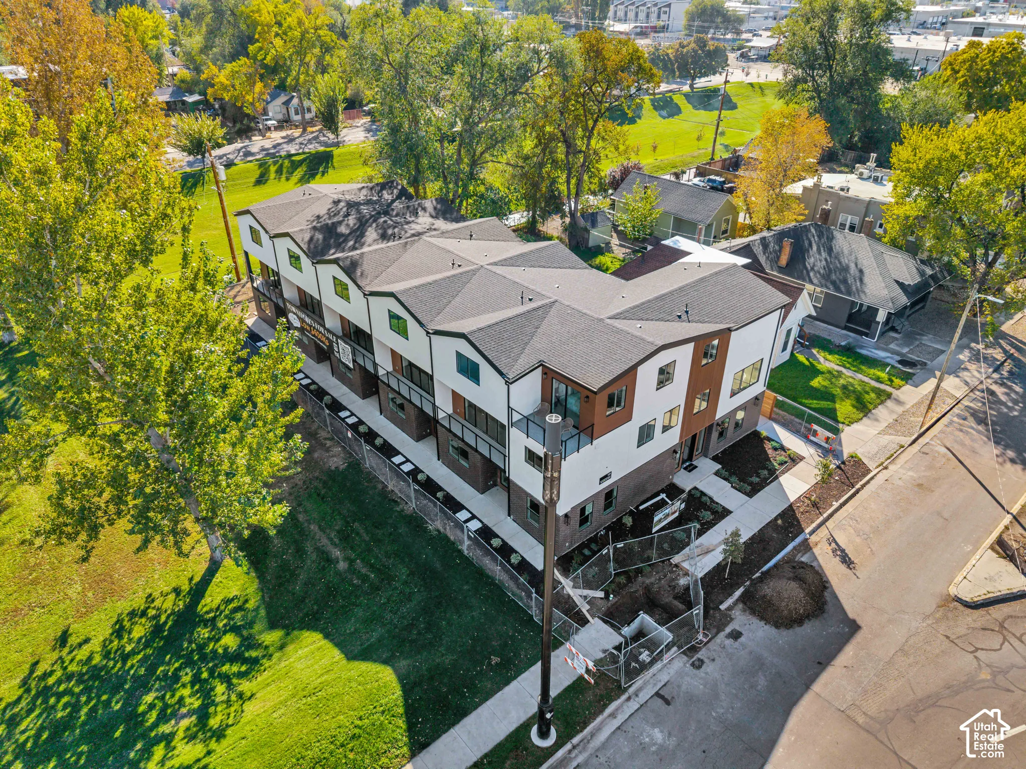 Multi-level exterior featuring a combination of brick and panel siding, dark-framed windows, integrated balconies with glass railings, and shingled rooflines