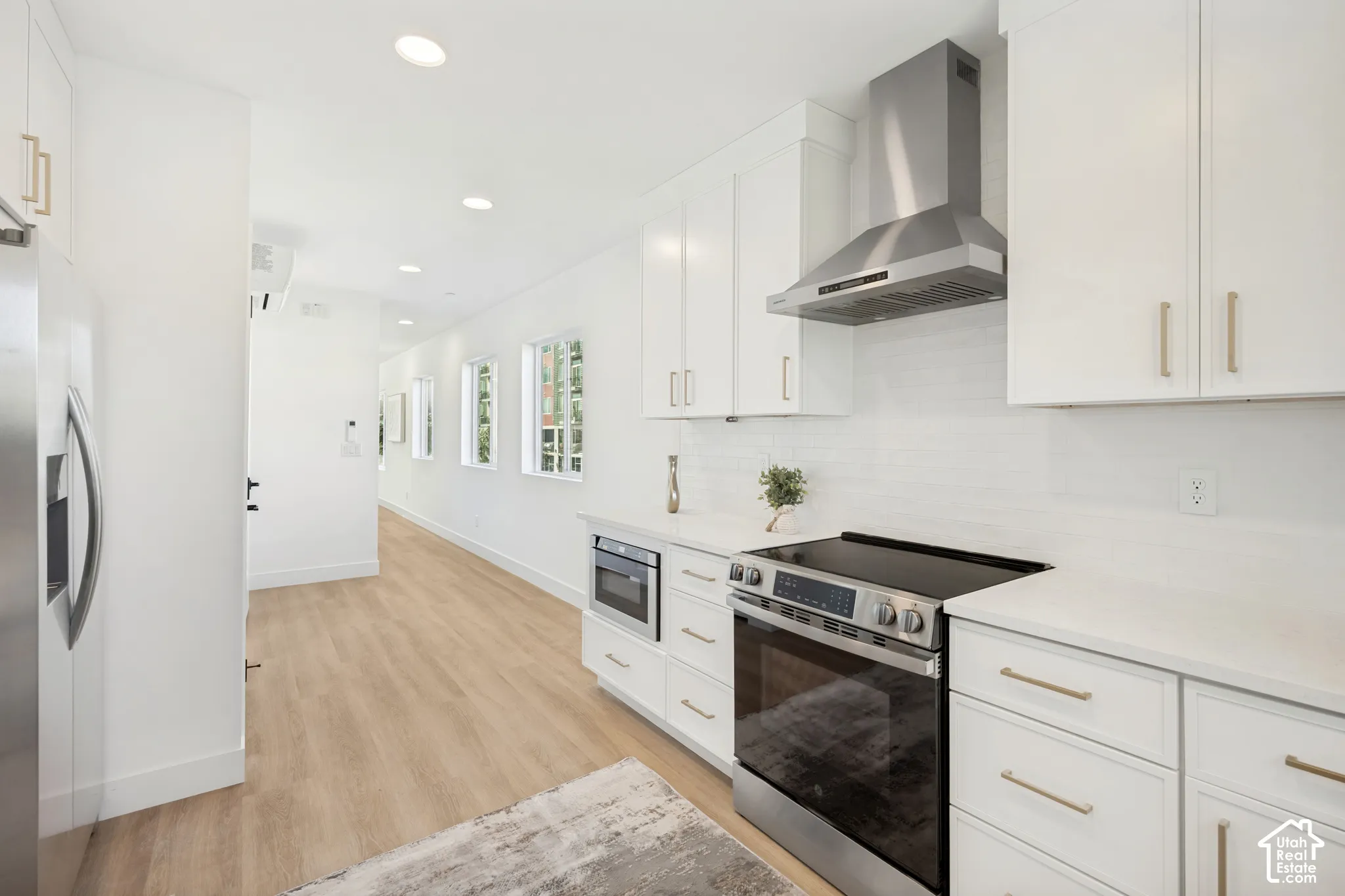 Kitchen featuring white cabinetry, quartz countertops, stainless steel appliances, a built-in microwave, and wood-finish flooring