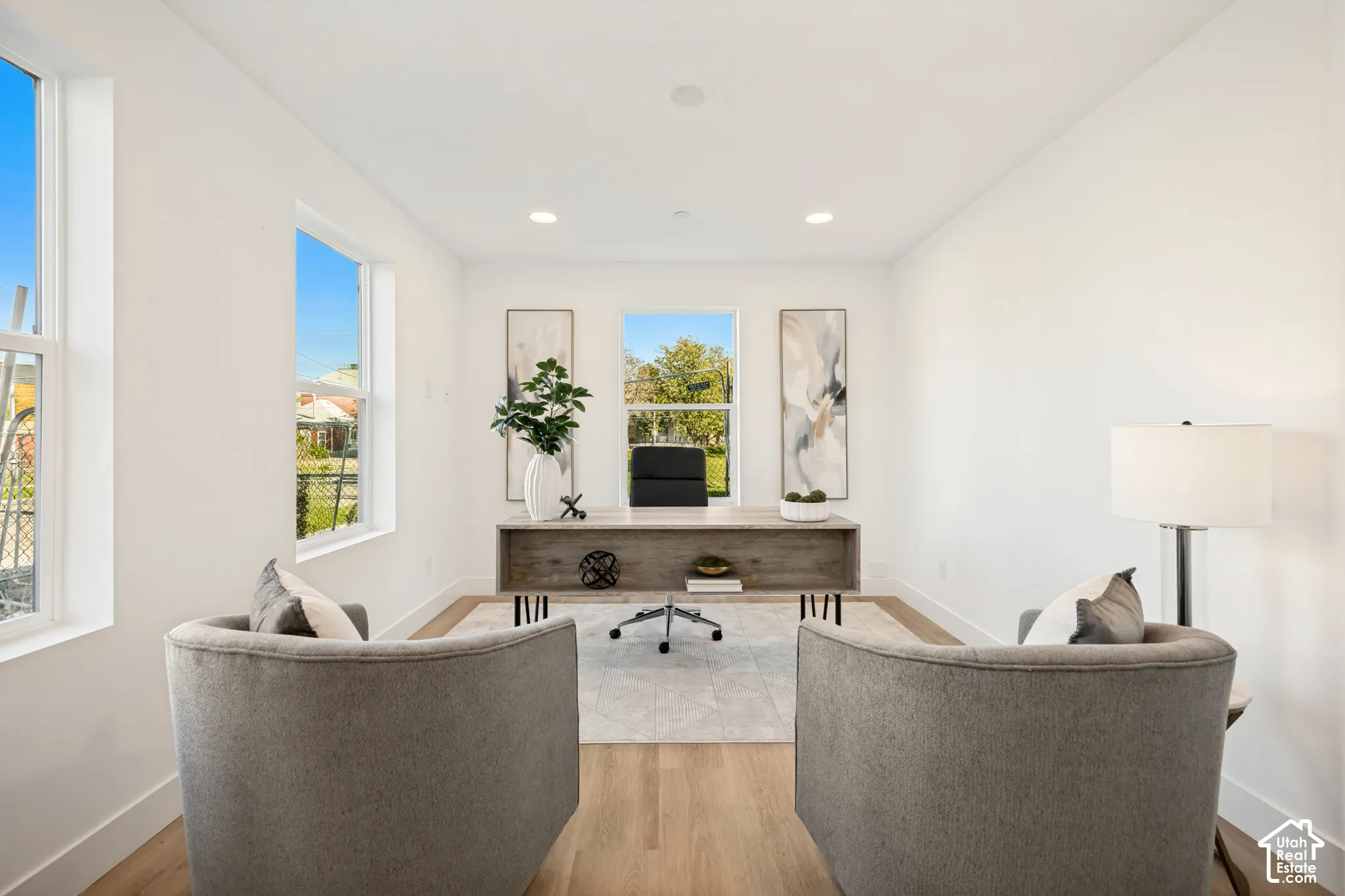 Bright room featuring wood-finish flooring, recessed lighting, and three large windows