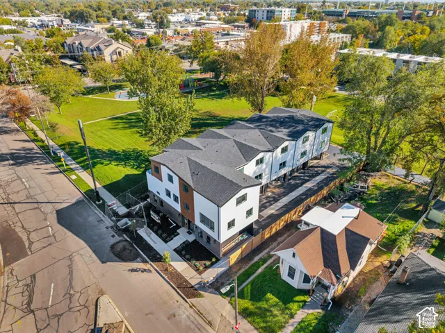 Multi-unit property featuring a mixed-material exterior, asphalt shingle roofing, paved surface parking, and a prominent position bordering an expansive landscaped park